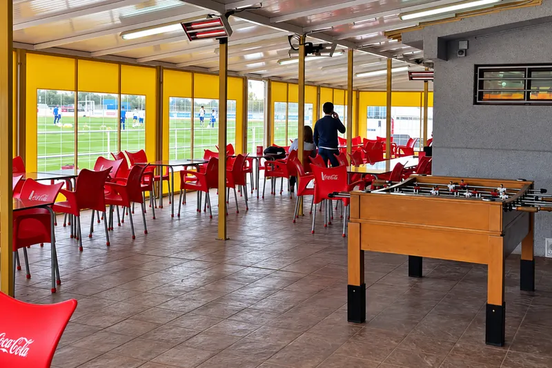 Café with tables, a table football game and large windows onto the pitch