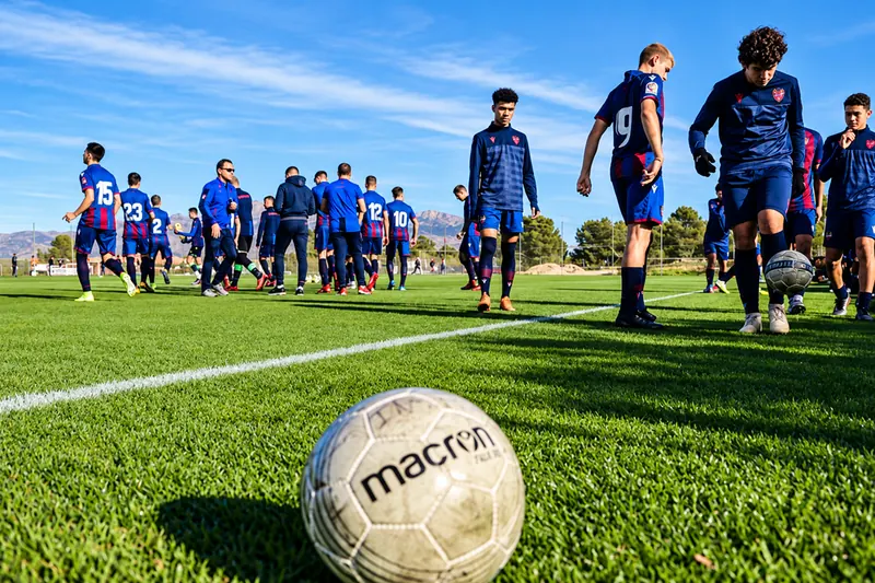 Group of players in the Levante UD kit on the grass, with a ball in the foreground