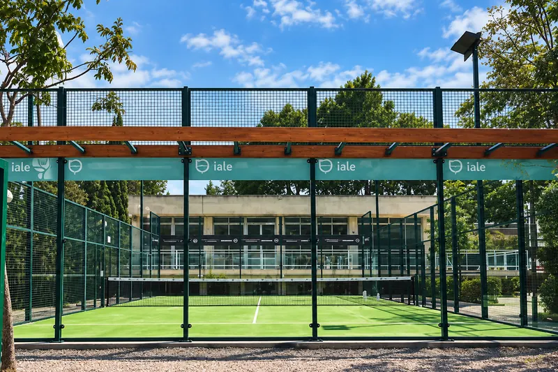 Glass-walled padel courts under a pergola