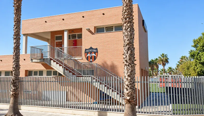 Edificio de la Escuela Patacona CF con el escudo del club en la fachada