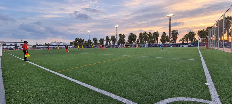 Match at sunset on the artificial grass pitch at Patacona CF Academy, with the assistant referee and flag in the foreground
